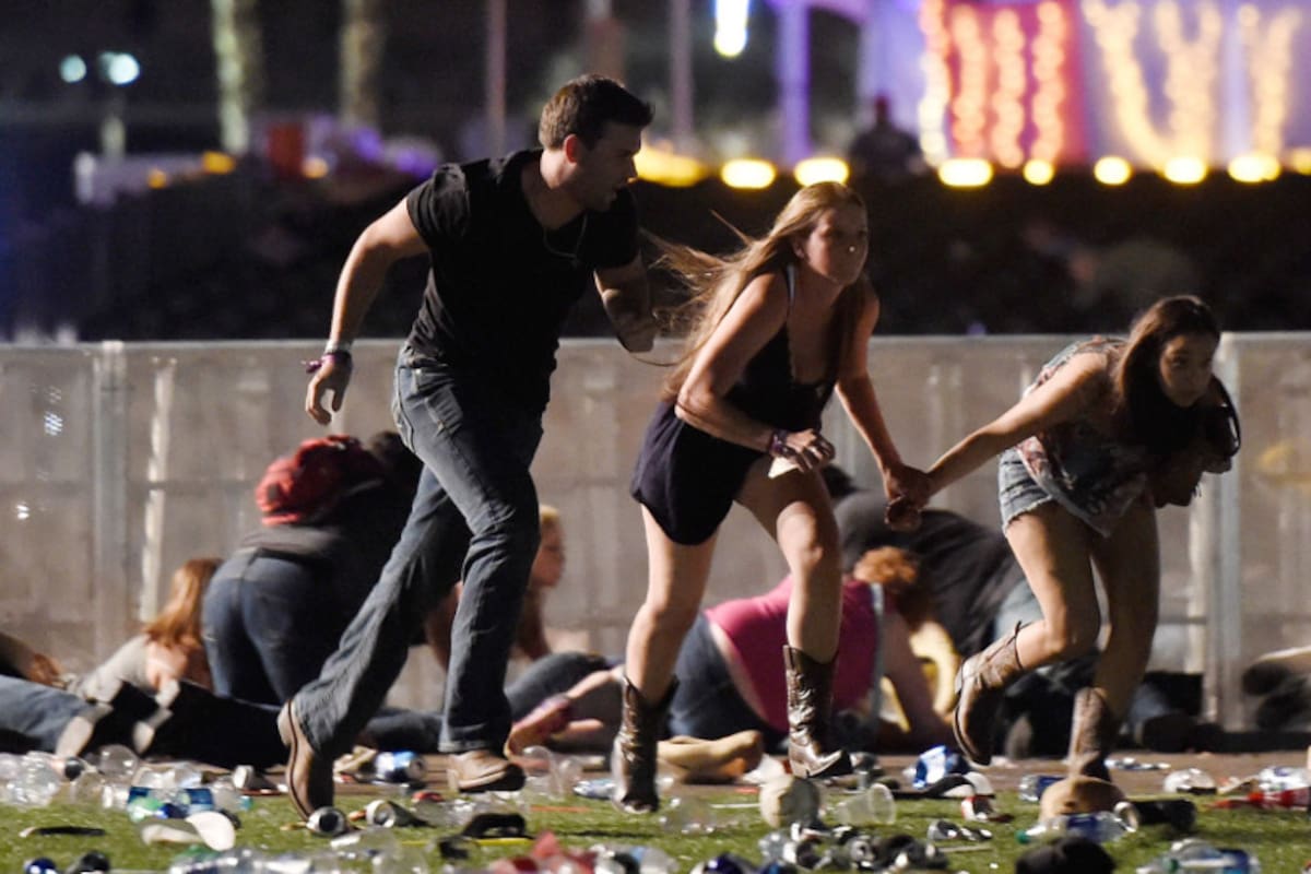 Tres asistentes al festival de música country en Las Vegas intentan refugiarse de la lluvia de balas disparadas por un tirador desde el hotel Mandalay Bay