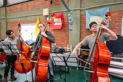 Tres contrabajistas ensayan en las instalaciones de la parroquia Madre del Pueblo, en el Bajo Flores, donde funciona el proyecto musical C.A.S.A