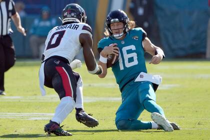 Trevor Lawrence (16), quarterback de los Jaguars de Jacksonville, se dezliza frente a Azeez Al-Shaair (0), linebacker de los Texans de Houston, durante la primera mitad del partido de la NFL del domingo 1 de diciembre de 2024, en Jacksonville, Florida. Lawrence resultó lesionado en la jugada. (AP Foto/John Raoux)
