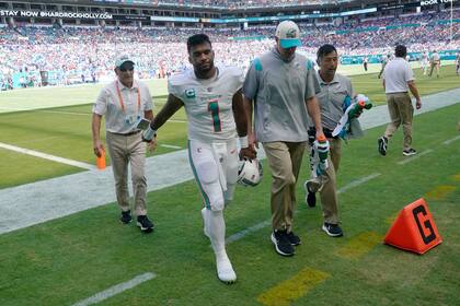 Tua Tagovailoa (1), quarterback de los Dolphins de Miami, es asistido para salir del terreno de juego después de resultar con una lesión durante la primera mitad del juego de la NFL entre Miami y los Bills de Buffalo, el domingo 25 de septiembre de 2022, en Miami Gardens, Florida. (AP Foto/Wilfredo Lee )