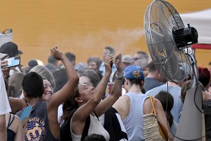 Turistas buscan refrescarse ante una ola de calor el año pasado en Roma, antes de entrar al Coliseo. (Tiziana FABI / AFP)