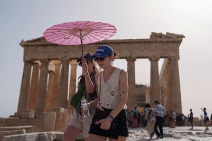 Turistas caminan por la Acrópolis, en Atenas, Grecia, bajo el fuerte calor, el 12 de junio de 2024. (AP Foto/Petros Giannakouris, Archivo)
