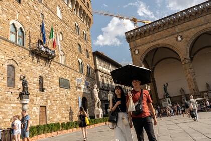 Turistas con paraguas, a manera de sombrilla en Florencia. La histórica ciudad enfrenta al desafío de hacerse más "verde" sin dañar su diseño de varios siglos de antigüedad