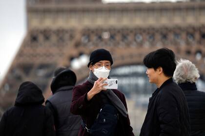 Turistas en París utilizan barbijos frente a la Torre Eiffel como medida de prevención