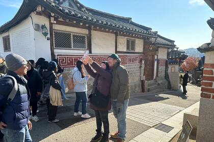 Turistas pasean haciendo fotos del vecindario residencial con viviendas tradicionales restauradas en el poblado de Bukchon Hanok, en Seúl, el miércoles 4 de diciembre de 2024. (AP Foto/ Jennifer McDermott)