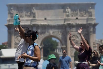 Turistas son rociados con agua para refrescarse frente al Arco de Constantino, junto al Coliseo, en Roma