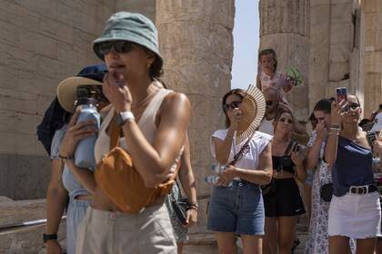 Turistas sufren la ola de calor afuera de la Acrópolis en Grecia