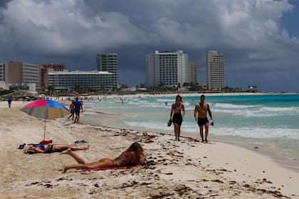 Turistas toman el sol en la playa antes de la llegada del huracán Grace, en Cancún, en el estado de Quintana Roo, México, el 18 de agosto de 2021. (AP Foto/Marco Ugarte)