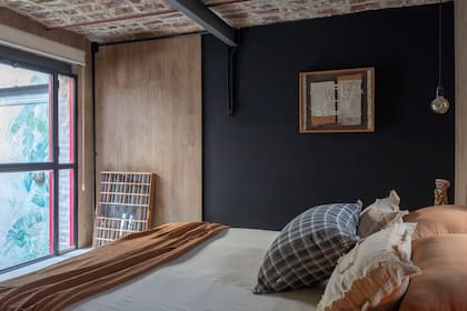 Ubicado en un entrepiso, el cuarto principal tiene revestimiento de pared (Patagonia Flooring)
y pintura color negro pizarra. Ropa de cama (Lote Propio).