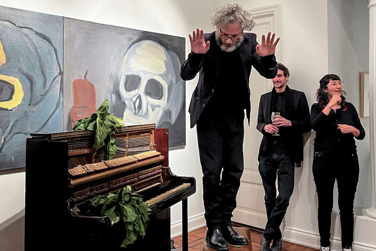 Ulises Conti junto al piano, el atado de acelga y la enorme pintura de Luis Frangella, en la galería Cosmocosa