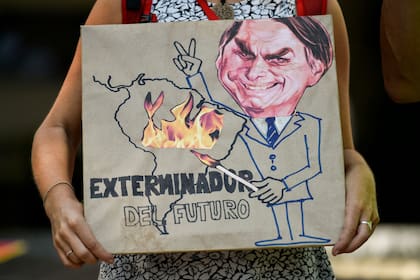 Un activista del cambio climático sostiene un cartel que representa al presidente brasileño Jair Bolsonaro con el lema "Exterminador del futuro", durante una protesta contra el líder brasileño por los incendios en la selva amazónica, frente al consulado brasileño en Cali, Colombia