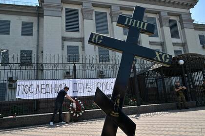 Un activista deposita una corona de flores simbólica frente a una pancarta en la que se lee "¡Último día de Rusia!" colocada en una valla frente a la embajada rusa en Kiev, la capital ucraniana, el 12 de junio de 2022