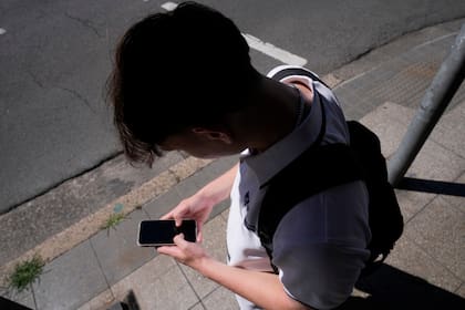 Un adolescente mira su teléfono, en Sydney (AP Foto/Rick Rycroft, Archivo)