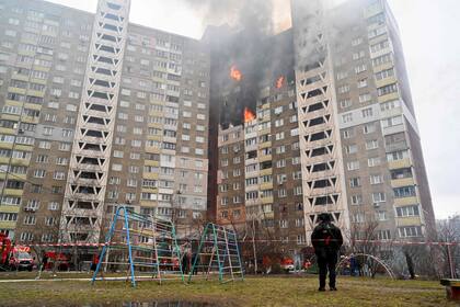 Un agente de la ley se encuentra junto a un edificio residencial, dañado como resultado de un ataque con misiles en Kiev el 7 de febrero de 2024, en medio de la invasión rusa de Ucrania.