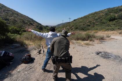 Un agente de la Oficina de Aduanas y Protección Fronteriza de Estados Unidos registra a un inmigrante que desea obtener asilo antes de que el hombre sea trasladado y procesado, cerca de Dulzura, California. (AP Foto/Gregory Bull).