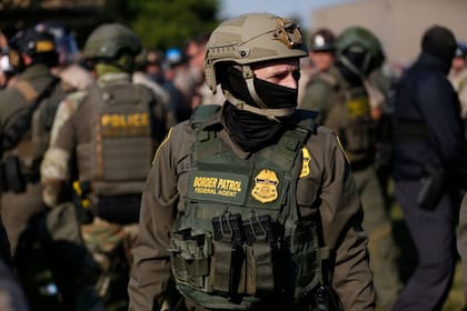 Un agente de la Oficina de Aduanas y Protección Fronteriza de EE. UU. (CBP) monta guardia mientras cientos de manifestantes se reúnen cerca de una instalación del Servicio de Inmigración y Control de Aduanas (ICE)
