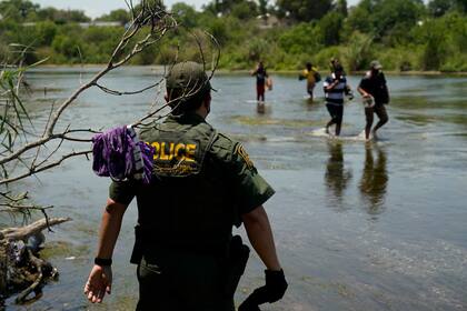 Un agente de la Patrulla Fronteriza de Estados Unidos junto con migrantes que cruzan el río Bravo cerca de Del Rio, Texas, el 15 de junio de 2021.   (Foto AP/Eric Gay, File)