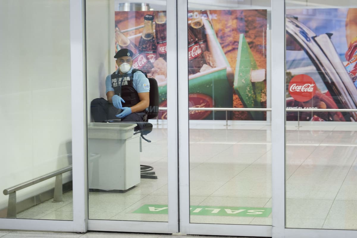 Un agente de la policía uruguaya, con máscara y guantes en el Aeropuerto de Carrasco