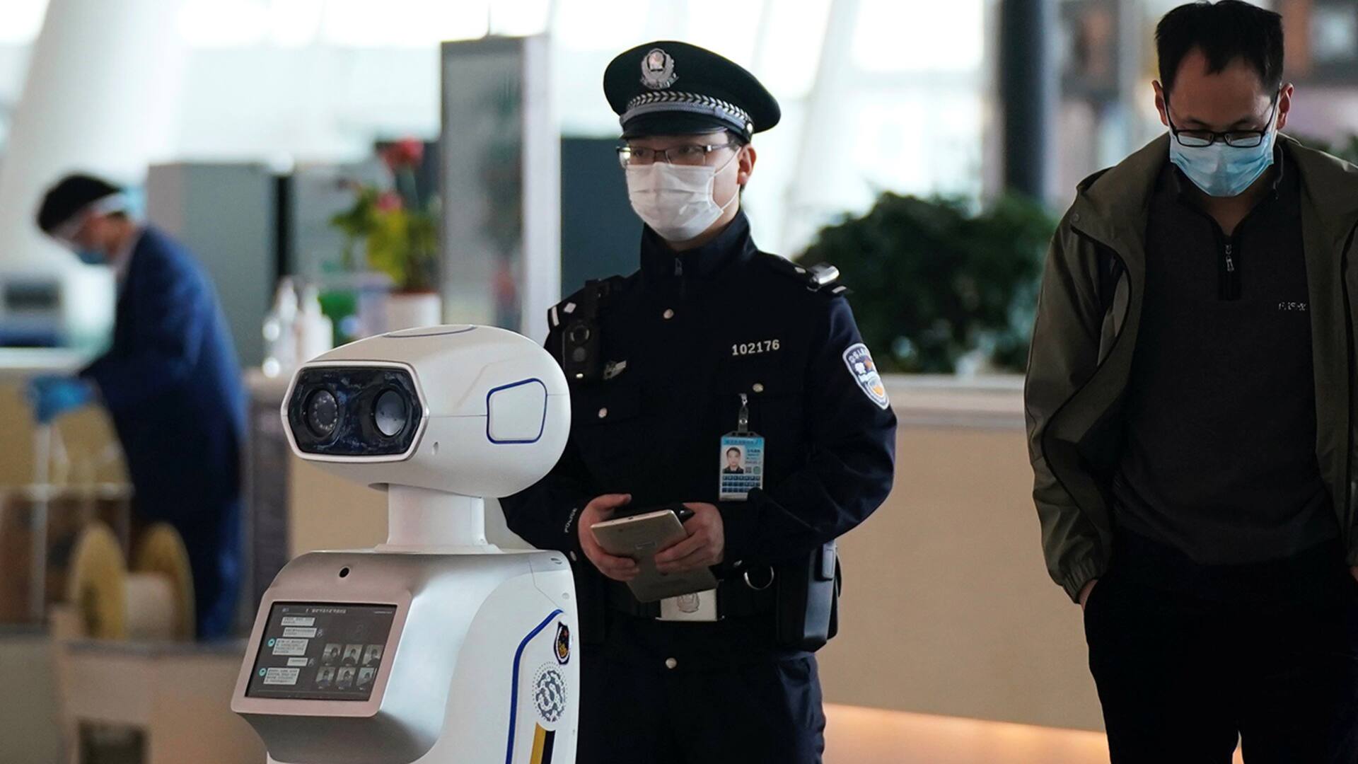 Un agente de segurida junto a un robot policía en el aeropuerto de Wuhan.