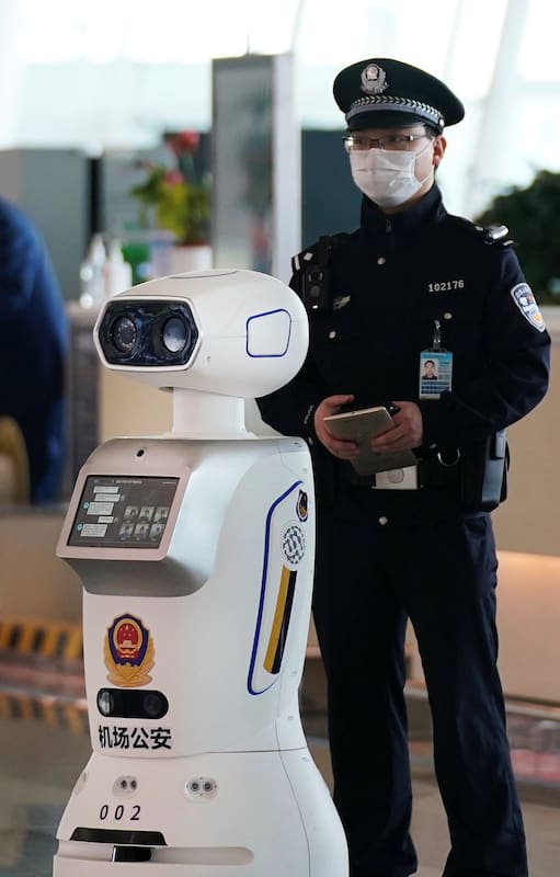 Un agente de segurida junto a un robot policía en el aeropuerto de Wuhan.