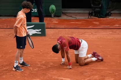 Un alcanzapelotas auxilia a Novak Djokovic tras sufrir una caída durante el partido de cuarta ronda contra Francisco Cerúndolo en el Abierto de Francia