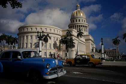 Un antiguo automóvil Lada de fabricación rusa, a la derecha, y un automóvil clásico de fabricación estadounidense pasan frente al Capitolio en La Habana, Cuba, el viernes 1 de abril de 2022. (AP Foto/Ramón Espinosa)