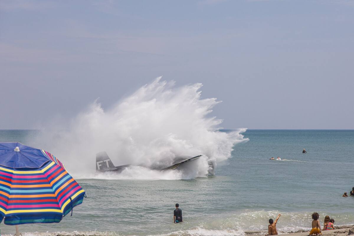 Un antiguo avión de la Segunda Guerra Mundial realizó un aterrizaje de emergencia en las aguas poco profundas de una playa colmada por una multitud de gente