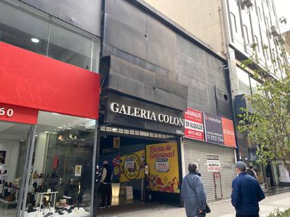Un "arbolito" se acerca a una mujer frente a la Galería Colón cerrada, en la calle Florida.