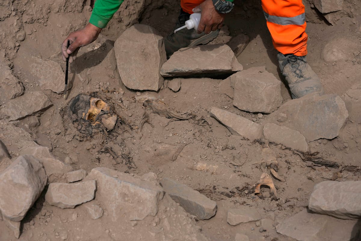 Un arqueólogo excava en la tumba de una momia prehispánica descubierta en una cima cercana a un campo de fútbol de un popular club peruano en el barrio de El Rimac de Lima, Perú, el jueves 15 de junio de 2023 (AP Foto/Martín Mejía)
