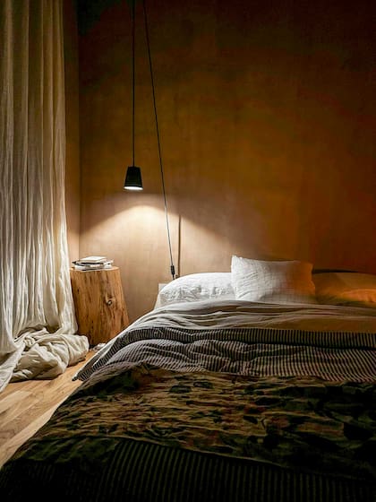 Un artefacto colgante alumbra la textura del adobe en un cuarto que no necesita más decoración