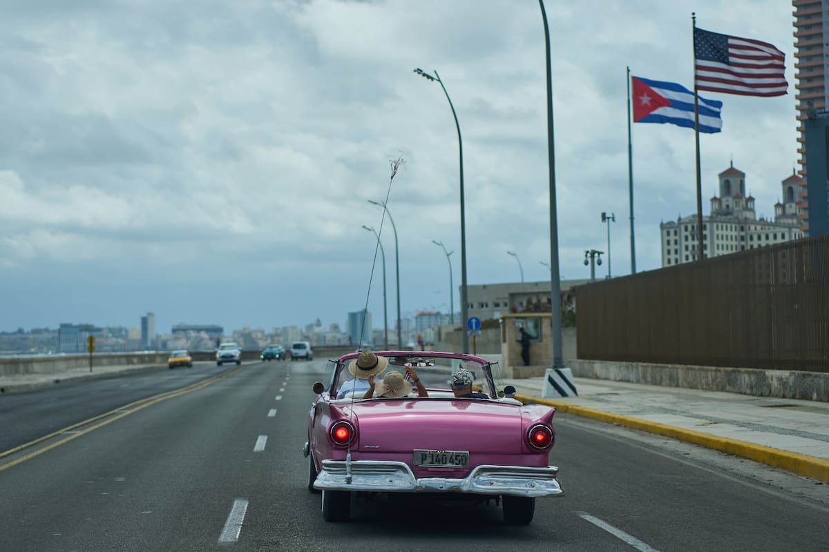 Un auto clásico estadounidense lleva a turistas junto a la embajada de Estados Unidos en La Habana