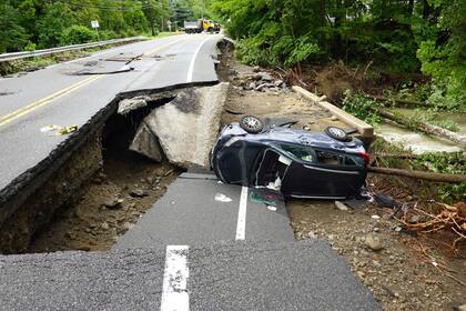 Un auto dañado se ve en un tramo de carretera derrumbado en la ruta 32 en el valle del Hudson, cerca de Cornwall, Nueva York, el lunes 10 de julio de 2023. (AP Foto/Paul Kazdan)