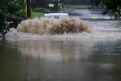 Un auto intenta cruzar una carretera anegada cerca de Peachtree Creek, Atlanta, tras el paso de la tormenta tropical Fred, el 17 de agosto de 2021. (AP Foto/Brynn Anderson)