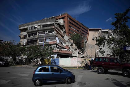 Un automóvil circula frente a edificios derrumbados tras un terremoto en Catia La Mar, estado La Guaira
