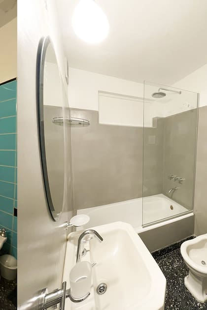 Un baño de época es modernizado cn microcemento, grifería nueva y accesorios como el espejo y la mampara