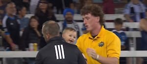 El momento en el que un bebé es retirado del campo de juego durante un partido de fútbol