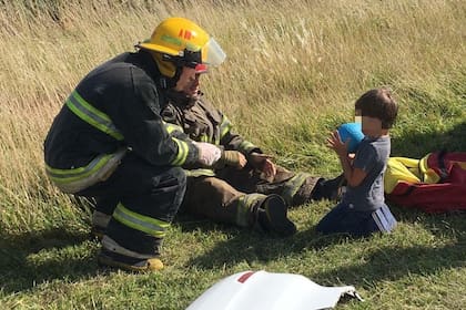 Dos bomberos de General Madariaga juegan con el menor luego de un accidente