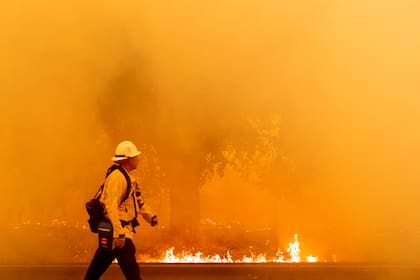 Un bombero de Pacific Gas and Electric camina por una carretera mientras las llamas se acercan en Fairfield, California durante el incendio del LNU Lightning Complex el 19 de agosto de 2020