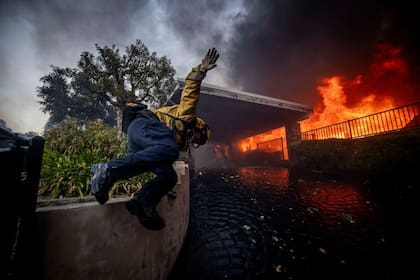 Un bombero salta sobre una valla en la zona de Palisades a 7 de enero de 2025.