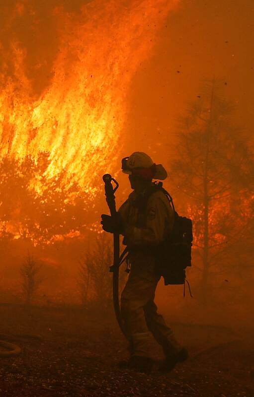 Un bombero vigila el incendio cerca de una casa en Paradise, California