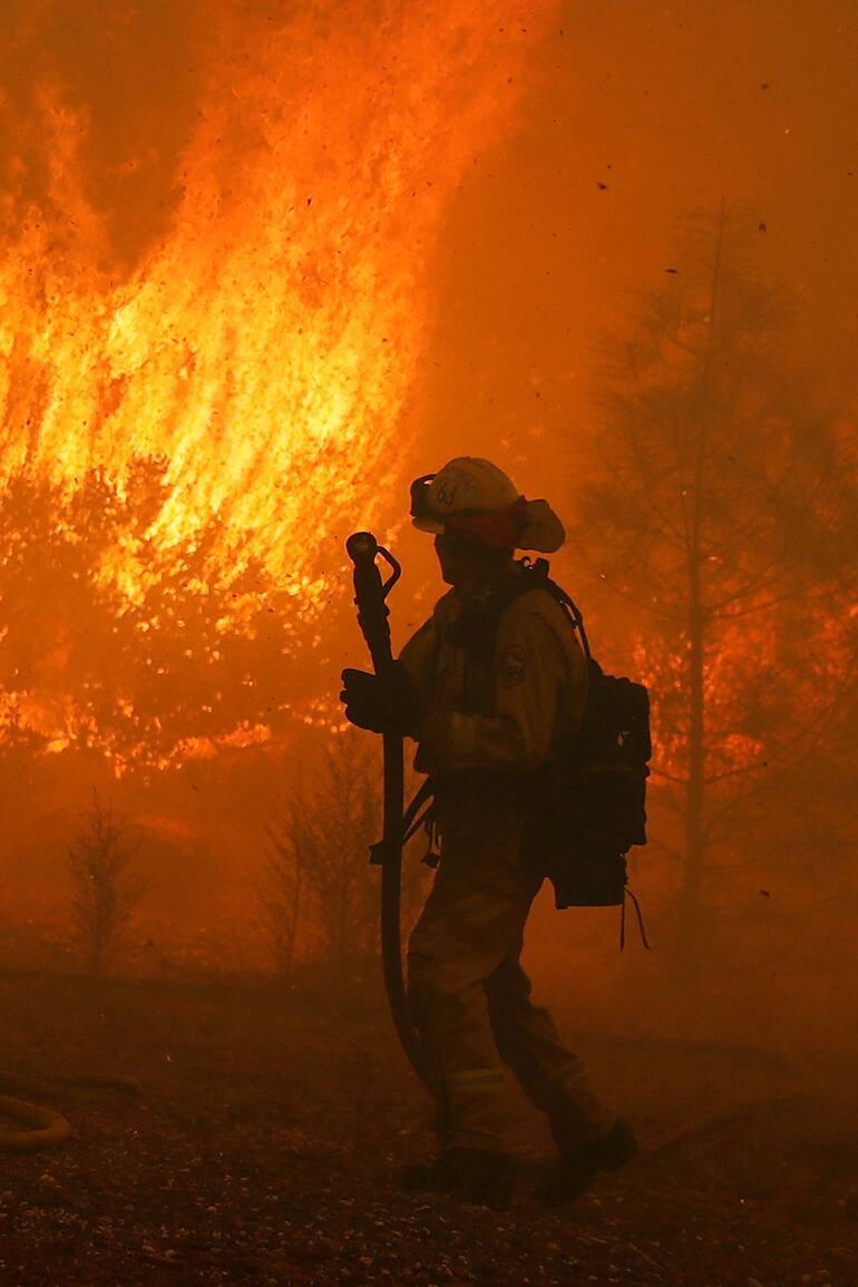 Un bombero vigila el incendio cerca de una casa en Paradise, California