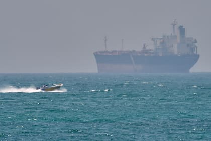 Un bote junto a un buque petrolero anclado en el estrecho de Ormuz