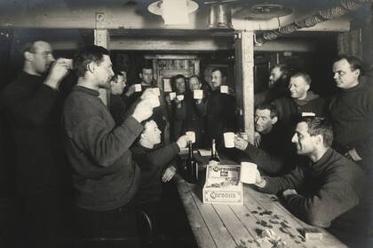 Un brindis el sábado por la noche por 'Sweethearts and Wives' a bordo del 'Endurance', durante la Expedición Imperial Transantártica, 1914-17, dirigida por Ernest Shackleton. (Foto de Frank Hurley/Scott Polar Research Institute, Universidad de Cambridge/Getty Images)