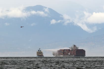 Un buque trabaja para controlar un incendio a bordo del MV Zim Kingston, el domingo 24 de octubre de 2021, a unos 8 kilómetros de la costa de Victoria, Canadá. (THE CANADIAN PRESS/Chad Hipolito/The Canadian Press vía AP)