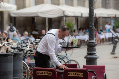 Un camarero limpia una mesa en la plaza Real de Barcelona, en Barcelona, Catalunya (España)