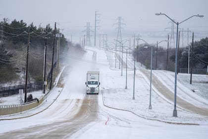 Un camión rueda sobre una vía cubierta de nieve durante la tormenta invernal del lunes 15 de enero en Grand Prairie, Texas (AP Photo/Julio Cortez)