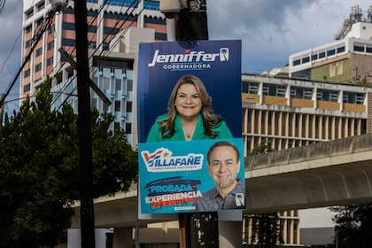 Un cartel de campaña promueve a Jenniffer González, candidata a la gobernación de Puerto Rico por el Partido Nuevo Progresista y actual comisionada residente de Puerto Rico en la Cámara de Representantes de Estados Unidos, arriba de un cartel del candidato a comisionado residente Luis Villafañe, vandalizado con las palabras "corrupta" y "pillo", el sábado 2 de noviembre de 2024, en San Juan, Puerto Rico. (AP Foto/Alejandro Granadillo)