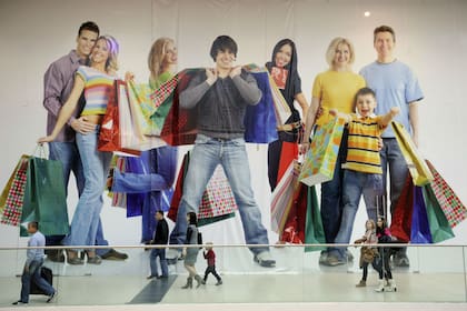 Un cartel gigante en un shopping que muestra a los consumidores con muchas bolsas