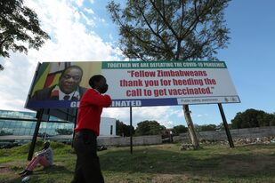 Un chico camina junto a un cartel con la imagen del presidente de Zimbabwe,  Emmerson Mnangagwa. El sur de África está en la mira por el brote de ómicron