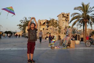 Un chico juega con un barrilete frente a la Ciudadela Medieval de Aleppo